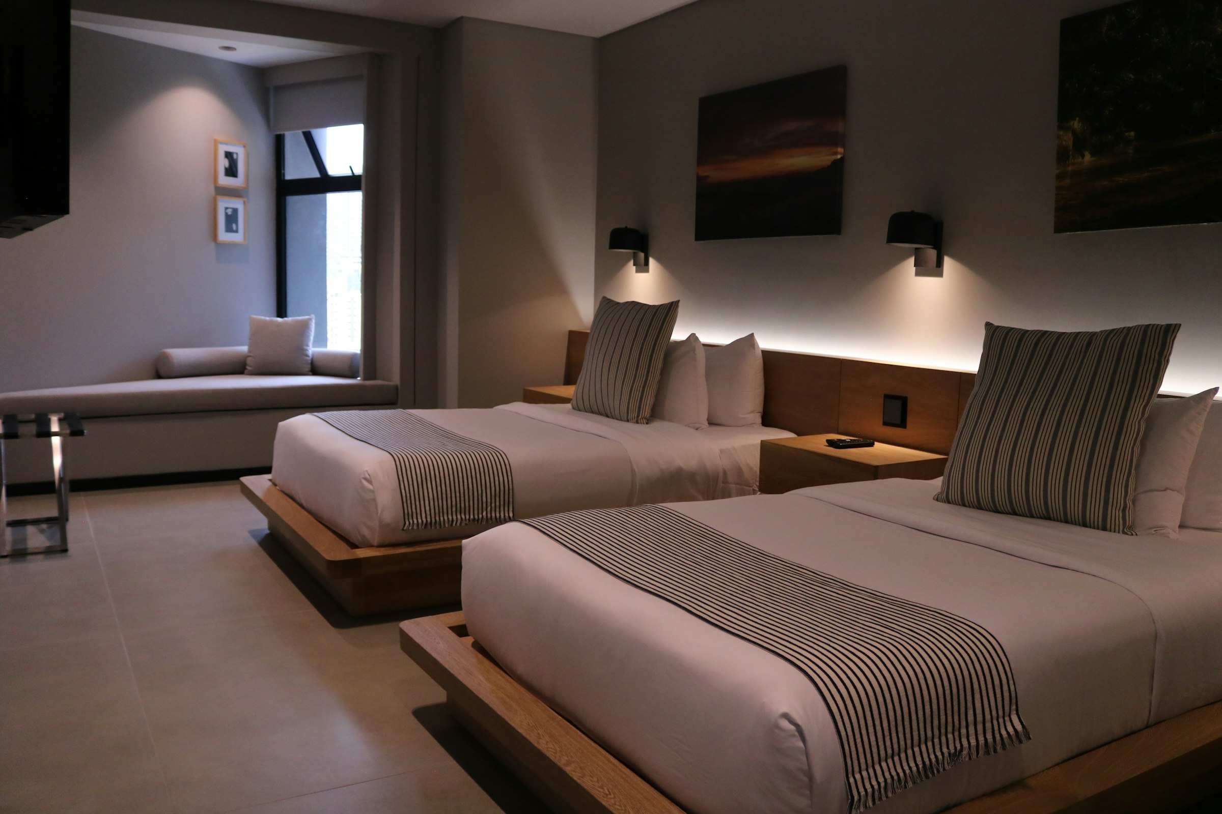 A hotel guest room with two assembled beds, a couch and case goods